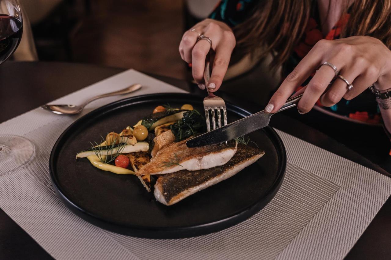 The H Dubai Hotel Exterior photo A woman using a knife and fork to cut into a fish fillet