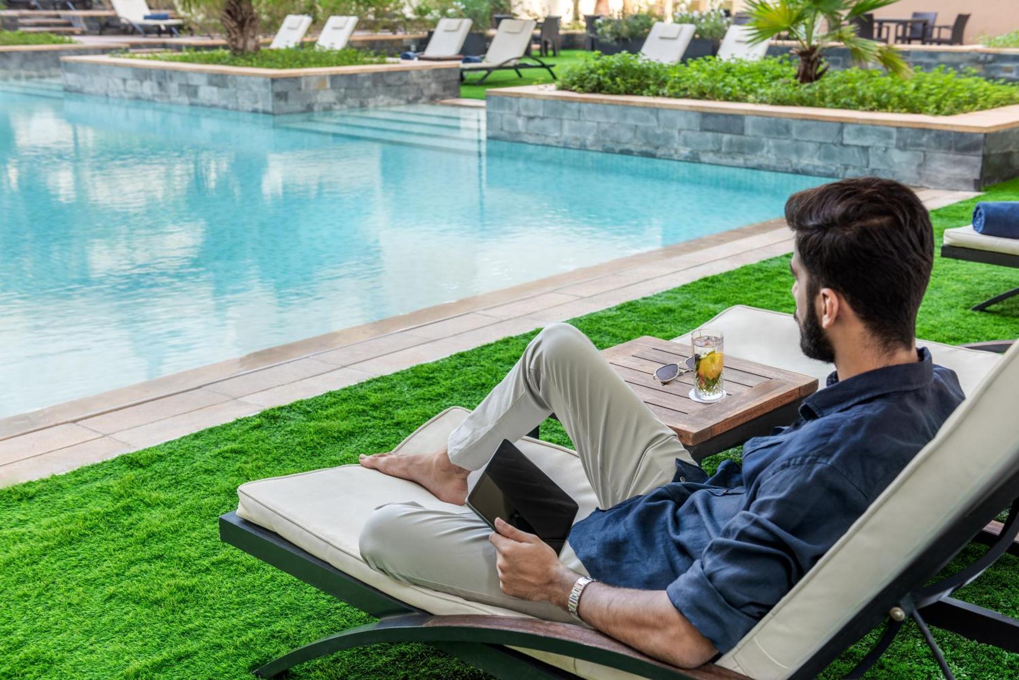 The H Dubai Hotel Exterior photo A man relaxing at the poolside